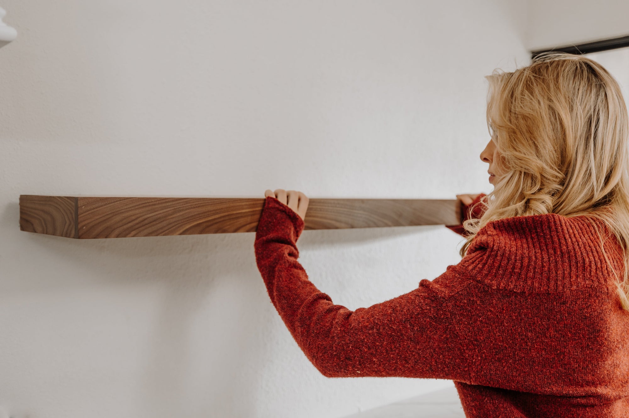 woman installing walnut floating shelf