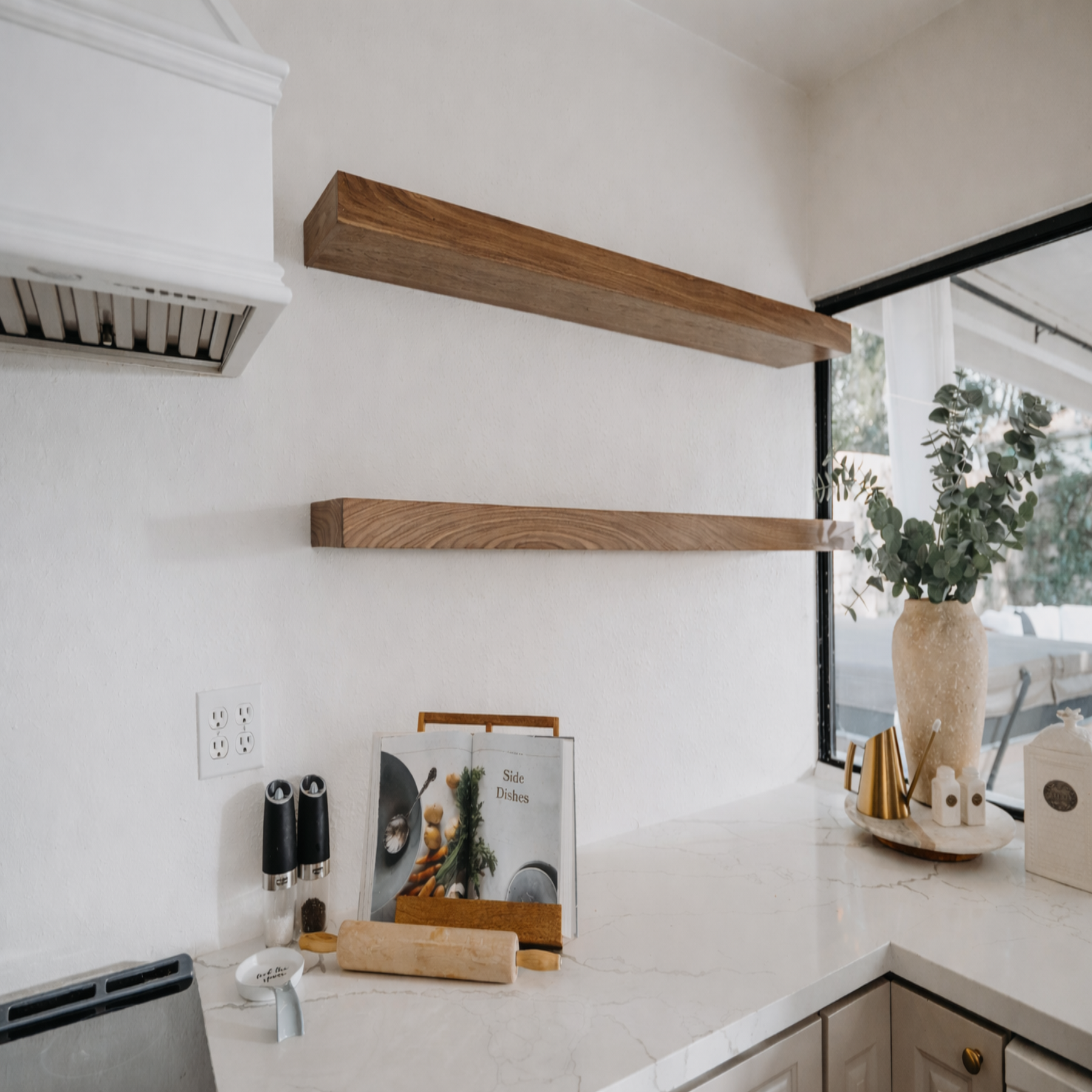 Modern kitchen with wooden shelves, countertop items, and a window view.