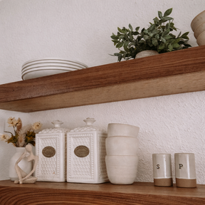 Wooden shelf with decorative items including ceramic jars, a plant, and small figurines.